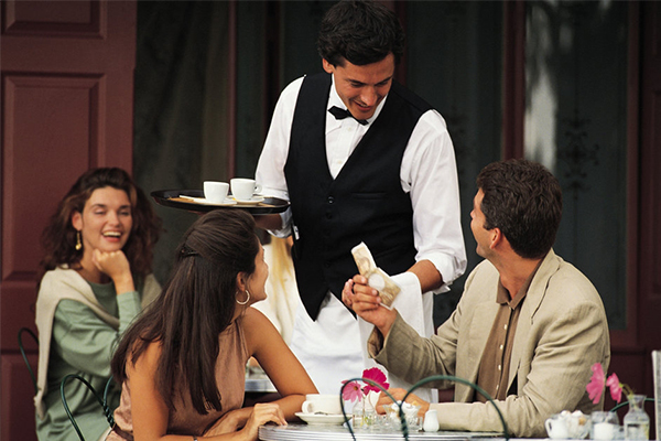 Happy couple and a waiter.